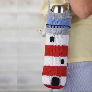 May include: A knitted red, white, and blue lighthouse-shaped bottle holder with a black strap. The bottle holder is made of yarn and has a black and white striped pattern.