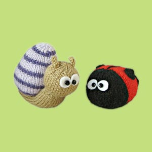 May include: Hand-knitted snail and ladybug toys. The snail has a tan body, a purple and white striped shell, and large googly eyes. The ladybug is red and black with googly eyes. Both are set against a light green background.