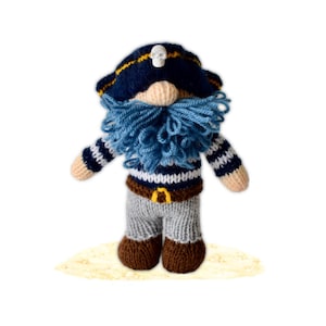 May include: A handcrafted, knitted pirate gnome with a blue and white striped sweater, gray pants, and brown boots. The gnome wears a navy blue pirate hat with a skull and crossbones and a blue beard. The gnome is standing on a sandy surface.