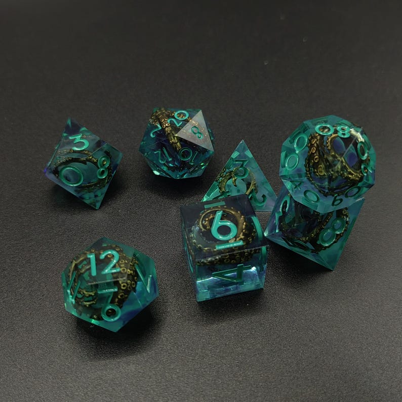 May include: A set of seven polyhedral dice made of translucent teal resin. Each die contains a dark, detailed octopus tentacle sculpture inside. The numbers on the faces are painted in a bright teal color, providing a clear contrast against the dark tentacles and the semi-transparent teal material of the dice.