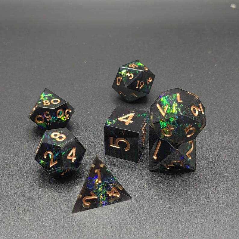 May include: A set of seven polyhedral dice made of black resin with embedded iridescent green and blue foil flakes. Each die features engraved numbers filled with a metallic copper finish, including a d20, d12, d10, d8, d6, and d4.