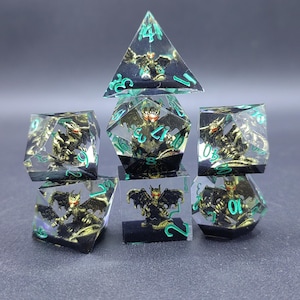 Può includere: Un set di sette dadi poliedrici in resina trasparente, ognuno contenente una miniatura di drago color oro con occhi rossi. I dadi presentano numeri incisi in verde brillante e sono disposti in una formazione impilata su sfondo scuro.