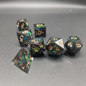 May include: A set of seven polyhedral dice made of black resin with embedded iridescent green and blue foil flakes. Each die features engraved numbers filled with a metallic copper finish, including a d20, d12, d10, d8, d6, d4, and a percentile die.