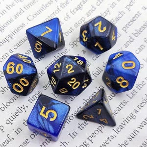 May include: Set of ten blue and black dice with gold numbers. The dice are made of a sparkly material and have a marbled effect.