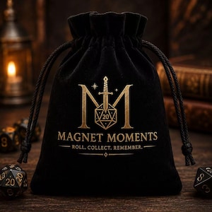 May include: A black velvet drawstring pouch featuring a gold-colored logo with a sword, a twenty-sided die, and the text MAGNET MOMENTS ROLL. COLLECT. REMEMBER. The bag is cinched at the top with black cords and sits on a dark wooden surface.