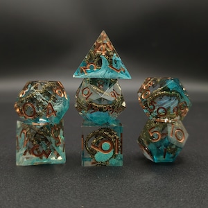 Puede incluir: Juego de siete dados poli&eacute;dricos con un dise&ntilde;o tem&aacute;tico marino. Los dados son transparentes con un patr&oacute;n de remolino turquesa y marr&oacute;n, y n&uacute;meros de color cobre. El juego incluye un d4, d6, d8, d10, d12, d20 y un cubo.