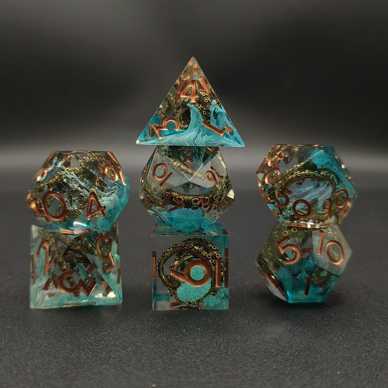 Puede incluir: Juego de siete dados poli&eacute;dricos con un dise&ntilde;o tem&aacute;tico marino. Los dados son transparentes con un patr&oacute;n de remolino turquesa y marr&oacute;n, y n&uacute;meros de color cobre. El juego incluye un d4, d6, d8, d10, d12, d20 y un cubo.