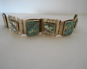 May include: A silver bracelet with five square-shaped compartments, each featuring a different iridescent abalone shell inlay.