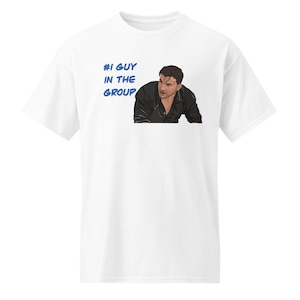 May include: White t-shirt with a blue graphic that says "#1 GUY IN THE GROUP" and a cartoon image of a man with dark hair.