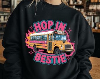 May include: Black sweatshirt with a yellow school bus graphic and the text "Hop in bestie" in pink and blue lettering.