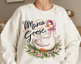 May include: White sweatshirt with a graphic of a goose wearing a pink bonnet and surrounded by green leaves and pink flowers. The text "Mama Goose, Est. 2025" is printed on the sweatshirt.