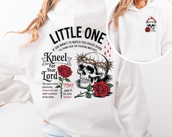 May include: White hoodie with a skull and roses graphic on the back. The text reads "Little One" and "Kneel For Your Lord".
