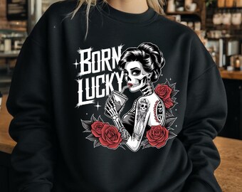 May include: Black sweatshirt with a graphic print of a skeleton woman with red roses and the text "Born Lucky".