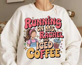 May include: White sweatshirt with the text "Running on Ms. Rachel and Iced Coffee" in pink, orange, and black. The graphic includes a cartoon of a girl with a pink headband and a cup of iced coffee.