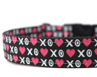 May include: A black dog collar with a pink and white pattern of hearts and "XO" symbols.