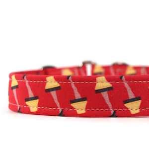 May include: Red dog collar with a repeating pattern of yellow lamps with black legs.