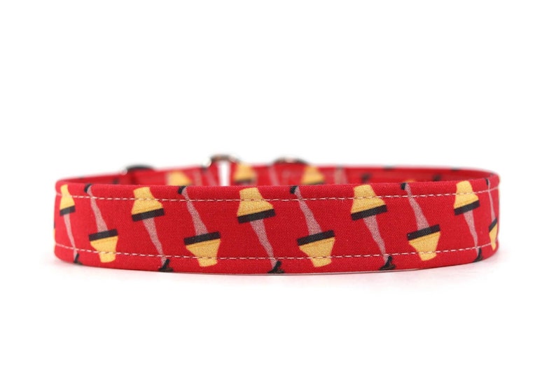 May include: Red dog collar with a repeating pattern of yellow lamps with black legs.