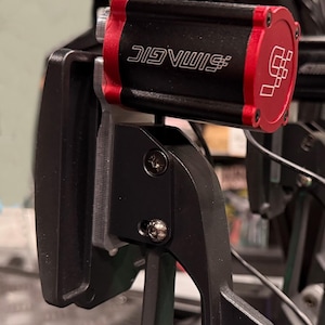 Könnte beinhalten: Ein schwarzes und rotes Rennspiel-Pedal mit dem Text "#SIMVUIC" auf der Seite.