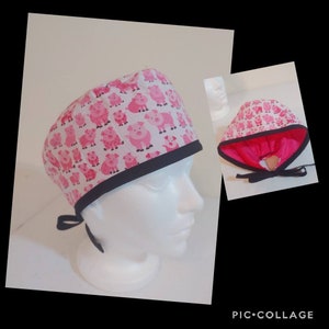 May include: A white surgical scrub cap featuring a repeating pattern of pink pigs. The cap has a black trim and ties in the back. A smaller image shows the cap's pink interior.