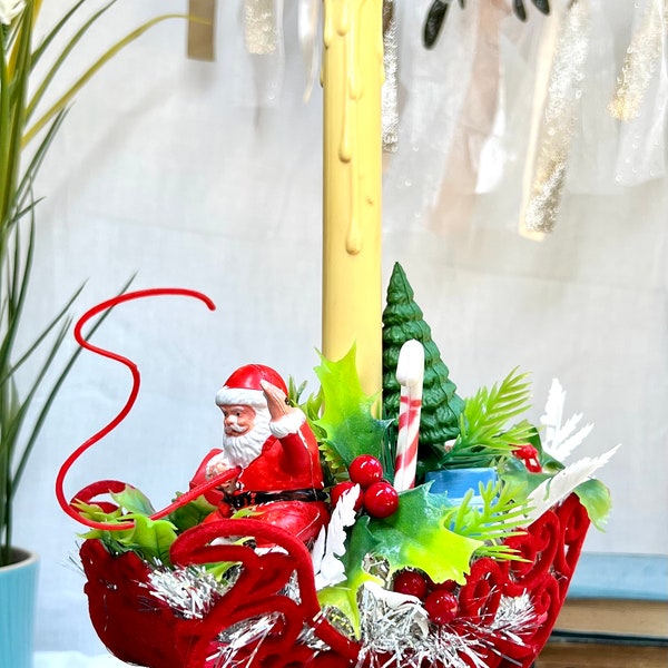 Vintage 1950's Santa in red velvet sleigh with retro candelabrum filled with greenery.