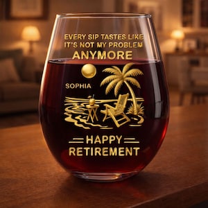 Puede incluir: Una copa de vino sin tallo llena de líquido rojo. La copa tiene letras doradas y un diseño tropical dorado con una palmera, una silla de playa y una pequeña mesa. El texto en la copa dice "EVERY SIP TASTES LIKE IT'S NOT MY PROBLEM ANYMORE" y "HAPPY RETIREMENT".
