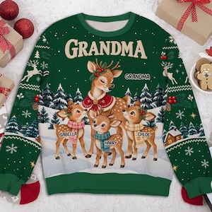 Könnte beinhalten: Ein dunkelgrünes Langarm-Sweatshirt mit einem weihnachtlichen Motiv eines Hirsches mit Brille und rotem Umhang, umgeben von drei Rehkitzen mit Schals. Der Text GRANDMA ist oben aufgedruckt, zusammen mit den Namen Isabella, Harry und Chloe.