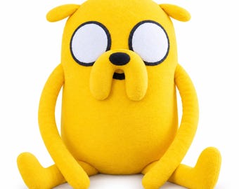May include: A yellow plush toy shaped like a dog with large white circular eyes, black outlines, a small black nose, and two drooping jowls. The character has long, thin arms and legs, small ears, and a rounded body, all made of soft yellow fabric.