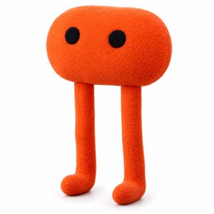 Puede incluir: Un peluche con una cabeza ovalada de color naranja brillante y dos pequeños ojos negros circulares. La figura tiene dos piernas largas y delgadas de color naranja que se extienden hacia abajo desde la base de la cabeza, terminando en pies redondeados.