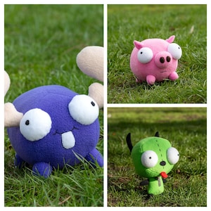 K&ouml;nnte beinhalten: Eine Collage von drei Pl&uuml;schtieren auf Gras. Eine lila Kreatur mit gro&szlig;en wei&szlig;en Augen und beigen Anh&auml;ngseln. Ein rosa Schwein mit gro&szlig;en wei&szlig;en Augen und einer schwarzen Schnauze. Eine gr&uuml;ne Figur mit schwarzen Antennen und einer roten Zunge.