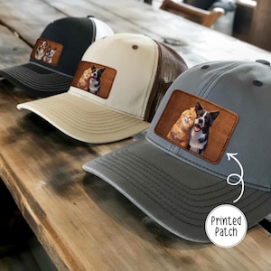 May include: Three baseball caps with a printed patch featuring a dog and cat. The caps are in black, tan, and gray, with mesh backs. The patches show a dog and cat in a loving embrace. The text "Printed Patch" is on the bottom right.