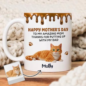 May include: White ceramic mug with a handle, featuring a cartoon orange tabby cat illustration. The mug has the text "HAPPY MOTHER'S DAY" and "TO MY AMAZING MOM THANKS FOR PUTTING UP WITH MY DAD". The cat's name "Molly" is also on the mug.