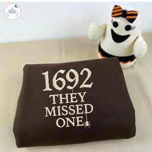 1692 They Missed One 刺繍入りトーンオントーンスウェットシャツ、ハロウィン刺繍シャツ、セーラムウィッチシャツ、セーラム1692シャツ ESS500.H.C