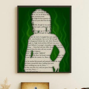 May include: A framed art print featuring a green silhouette of a person against a backdrop of green swirls and text from a book. The text is in black and is partially visible, adding a literary element to the artwork.