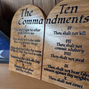 May include: Two wooden plaques with the Ten Commandments engraved in black lettering. The plaques are made of cherry wood and have a natural finish. The text on the plaques is in English.