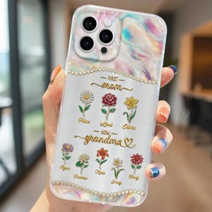 May include: Clear phone case with a colorful marble design and a decorative border. The case features the text "FIRST mom - NOW grandma" with floral accents and names. The case is designed to fit a smartphone.