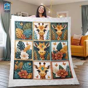 Op de afbeelding: Witte quilt met negen vierkante panelen met illustraties van giraffen. Elk paneel toont een giraffengezicht omringd door tropische bladeren, bloemen en vlinders. De quilt heeft een diamantgestikt patroon.