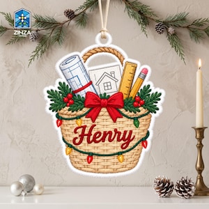 以下が含まれることがあります： 「Henry」という名前が赤字で書かれた、編みかご型のクリスマスオーナメント。かごの中には、丸められた設計図、家の絵、定規、鉛筆が入っており、緑の松の枝、赤い実、ライトで装飾されています。