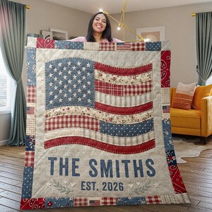 May include: A patchwork quilt with an American flag design. The quilt features a blue field of stars and red and white stripes. The text "THE SMITHS EST. 2026" is displayed at the bottom. The quilt is made of various patterned fabrics.