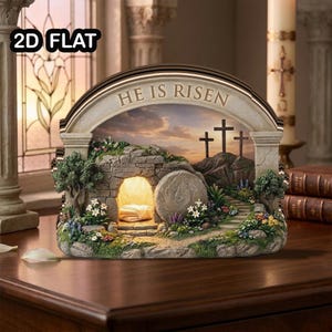 Puede incluir: Una escena religiosa decorativa con una tumba de piedra, una entrada abierta y las palabras "HE IS RISEN" arriba. La escena incluye tres cruces en una colina, un camino y flores coloridas. El diseño es detallado e iluminado.