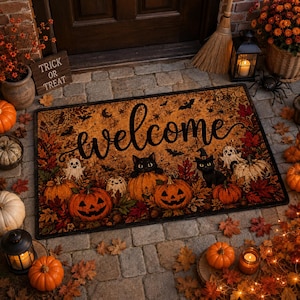 Puede incluir: Un felpudo rectangular con temática de Halloween que presenta la palabra welcome en letra cursiva negra. El diseño incluye calabazas naranjas, gatos negros, fantasmas blancos, murciélagos, telarañas y hojas de otoño en tonos rojos, naranjas y marrones.