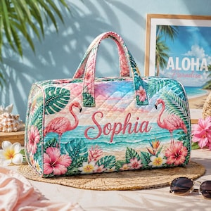 May include: A quilted duffel bag featuring a tropical beach scene with pink flamingos, green palm leaves, and pink hibiscus flowers. The name Sophia is printed in a cursive script across the centre of the bag, which has two top handles.
