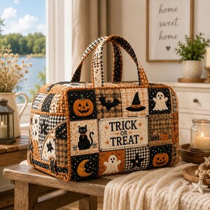 Può includere: Una borsa in tessuto trapuntato con un design patchwork a tema Halloween che include zucche, gatti neri, fantasmi, pipistrelli, stelle e lune. Il pannello centrale mostra la scritta TRICK OR TREAT in lettere nere su sfondo color crema.