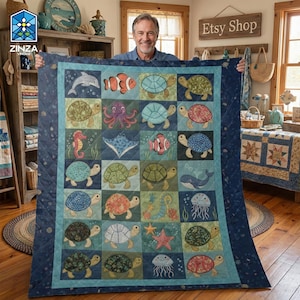 以下が含まれることがあります： 海洋生物をテーマにした、大きな正方形のキルト。キルトは、それぞれ異なる海の生き物（カメ、魚、クジラなど）を描いたカラフルな正方形のグリッドを表示しています。キルトは濃い青色のボーダーと薄い青色の内側のボーダーが付いています。