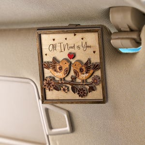 May include: Wooden framed artwork featuring two birds perched on a branch with flowers. The artwork includes the text "All I Need is You" and a red heart. The birds have the names "James" and "Sophia" below them.