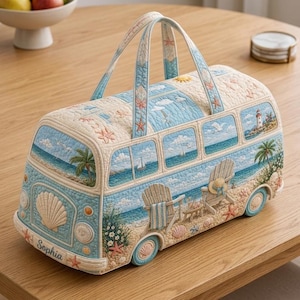 Puede incluir: Un bolso de tela acolchada con forma de furgoneta vintage, que muestra una escena de playa con palmeras, sillas y un faro. El exterior en azul claro y crema presenta el nombre Sophia en el parachoques delantero, decorado con estrellas de mar.