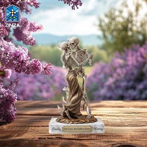 Puede incluir: Figura decorativa de dos esqueletos abrazándose, uno con una prenda drapeada. La base está inscrita con "Emily Our Love, An Endless Dance Henry". El fondo presenta flores moradas y una escena exterior borrosa.
