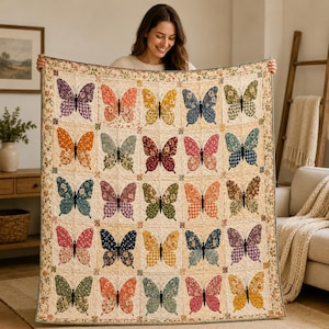 May include: A rectangular quilt featuring a grid of twenty-five butterfly appliques in various colors and floral or checkered patterns. The quilt has a cream-colored background and a decorative floral border, with each butterfly centered in a square.
