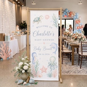 May include: A vertical rectangular banner on a wooden stand featuring watercolor illustrations of a sea turtle, dolphin, seahorse, octopus, and starfish. Text reads: Welcome to Charlotte's Baby Shower, Baby Bennett, and the date 08.16.2026.