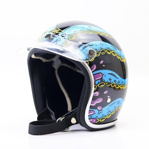 Op de afbeelding: Zwarte motorhelm met een helder vizier. De helm heeft een ontwerp van blauwe golven met gele en paarse accenten. Hij heeft een zwarte kinband en een witte rand aan de basis.