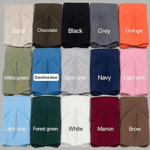 May include: A hoodie color chart featuring fifteen folded hoodies in various colors arranged in a grid. The text HOODIE COLOR CHART appears at the top. Colors include sand, chocolate, black, grey, orange, military green, Carolina blue, sport grey, navy, light pink, light blue, forest green, white, maroon, and brown.
